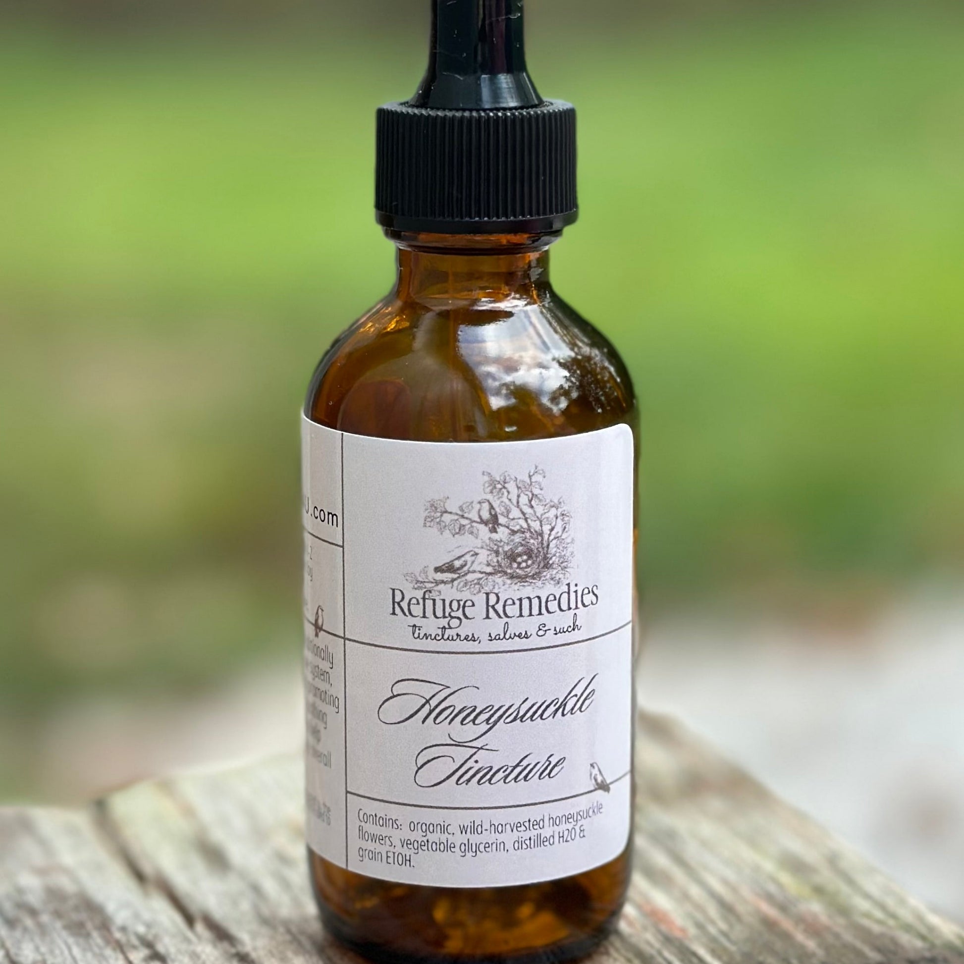 Bottle of Refuge Remedies Honeysuckle Tincture on a wooden surface with a blurred natural background