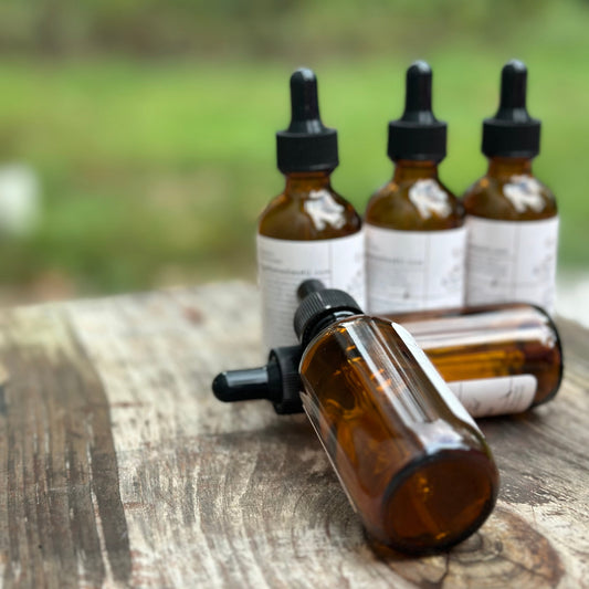 Three brown glass bottles with dropper caps on a wooden surface with a blurred natural background.