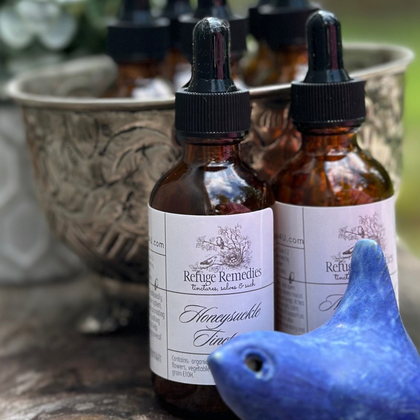 Amber glass bottles with dropper lids on a stone surface with a blue bird figurine.