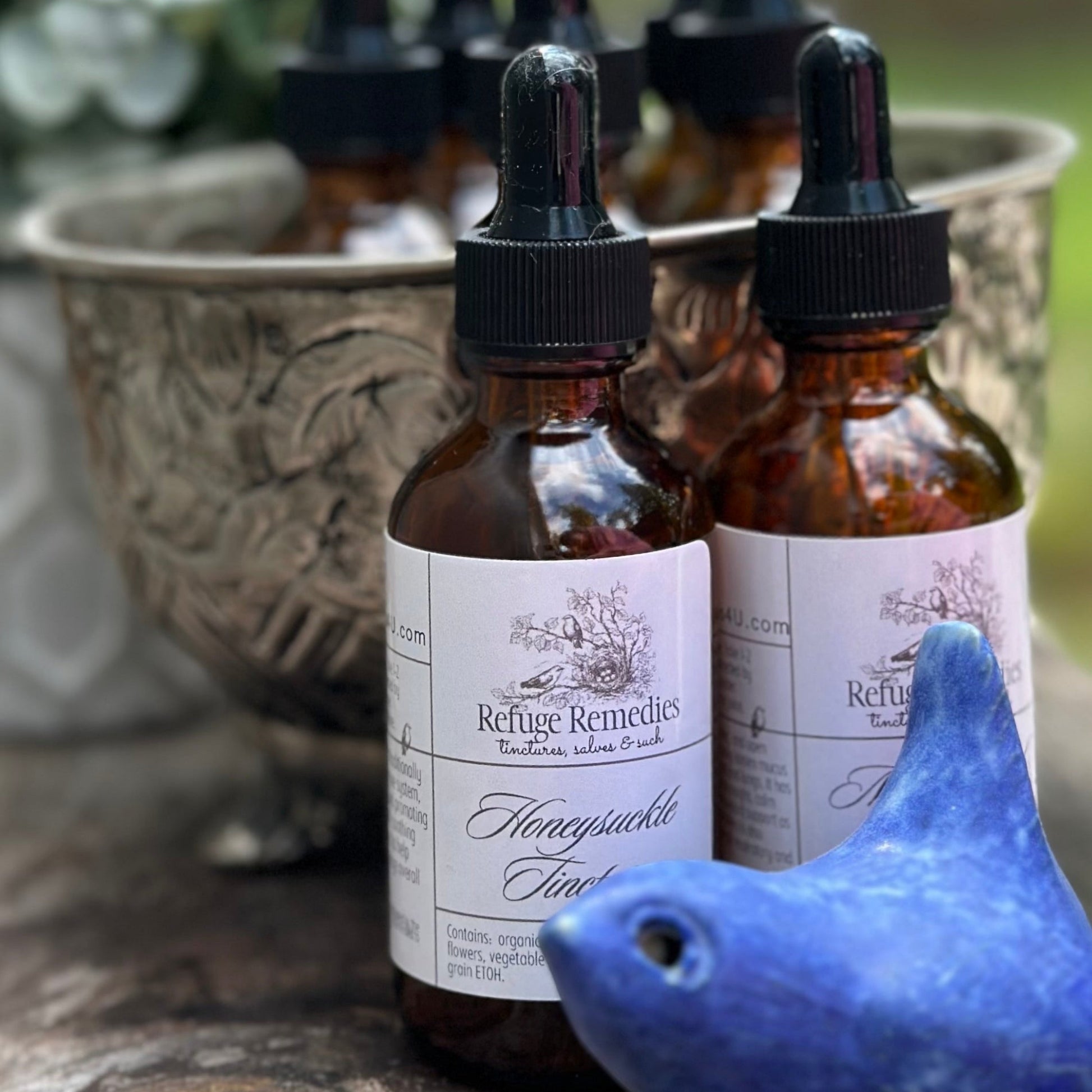 Amber glass bottles with dropper lids on a stone surface with a blue bird figurine.